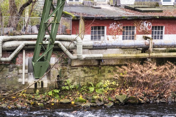 District heating pipeline in front of old industrial buildings on the banks of the Wupper, Wuppertal, Germany