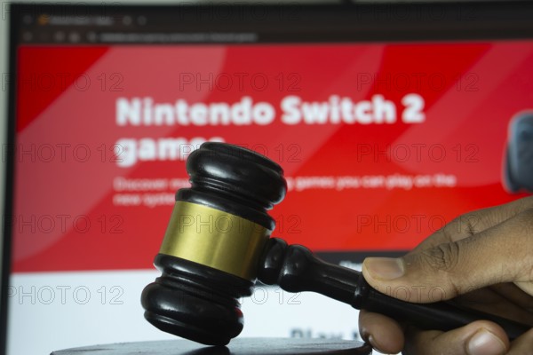 Dhaka, Bangladesh- 20 June 2025: A hand holds a gavel in front of a computer screen displaying Nintendo's website