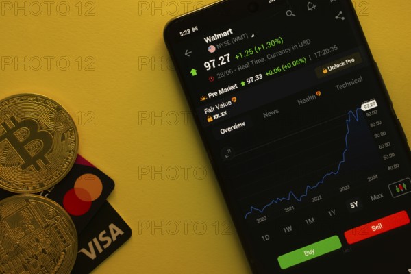 Dhaka, Bangladesh- 30 June 2025: Smartphone displaying Walmart stock data on a trading app with Bitcoin, Visa and Mastercard card on a vibrant yellow background