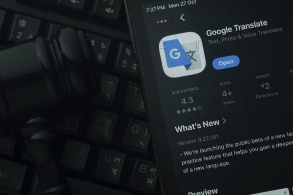 Dhaka, Bangladesh- 28 Oct 2025: An iPad displaying the Google Translate app against a judge's gavel and dark keyboard background