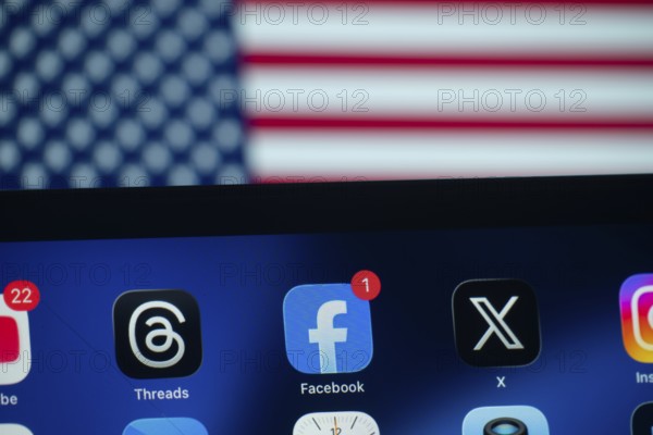Dhaka, Bangladesh- 01 Dec 2025: A smartphone screen displays the Facebook, Youtube, X, Threads, Instagram app with an USA flag in the background