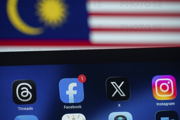 Dhaka, Bangladesh- 01 Dec 2025: Facebook, X, Threads, Instagram apps are displayed on a smartphone screen, and the Malaysian flag is visible in the background