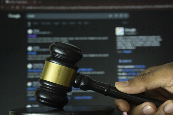 Dhaka, Bangladesh- 20 June 2025: A hand holds a gavel in front of a computer screen displaying Google's website