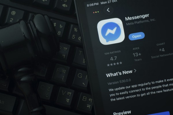 Dhaka, Bangladesh- 28 Oct 2025: An iPad displaying the Messenger app against a judge's gavel and dark keyboard background