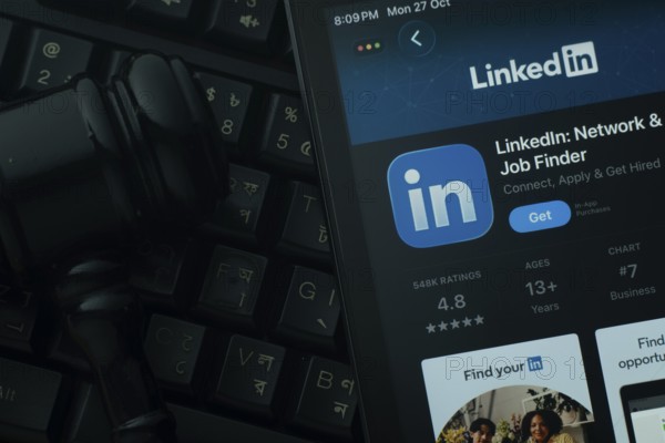 Dhaka, Bangladesh- 28 Oct 2025: An iPad displaying the LinkedIn app against a judge's gavel and dark keyboard background