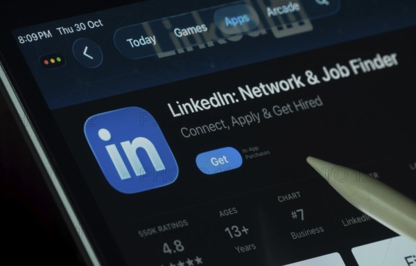 Dhaka, Bangladesh- 30 Oct 2025: LinkedIn app displayed on a iPad screen in dark mode with a digital pen pointing at it