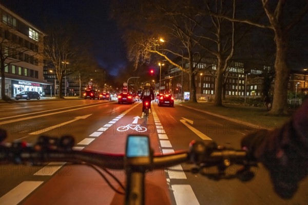 Cycling in the city, in the dark, in the evening, cycling on a bike lane, marked in red, Huyssenallee, in downtown Essen, North Rhine-Westphalia, Germany