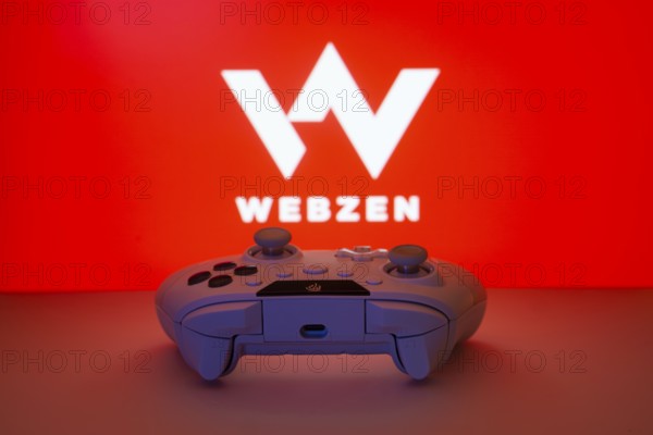 Dhaka, Bangladesh- 14 Nov 2025: A close-up of a white gamepad with the Webzen seen on screen in the background
