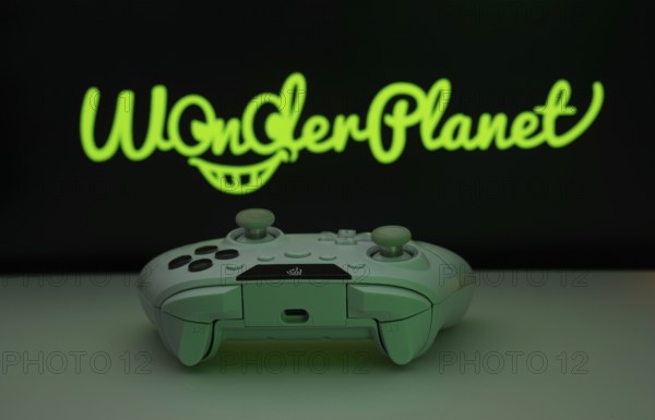 Dhaka, Bangladesh- 14 Nov 2025: A close-up of a white gamepad with the WonderPlanet Inc seen on screen in the background