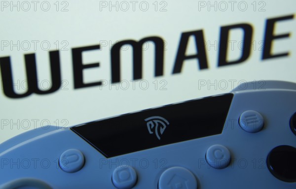 Dhaka, Bangladesh- 14 Nov 2025: A close-up of a gamepad with the WeMade Entertainment seen on screen in the background
