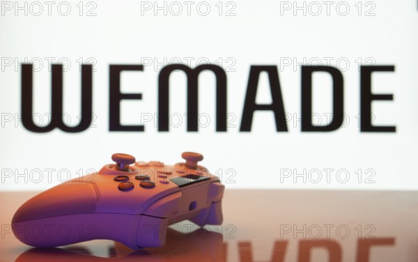 Dhaka, Bangladesh- 14 Nov 2025: A close-up of a white gamepad with the WeMade Entertainment seen on screen in the background