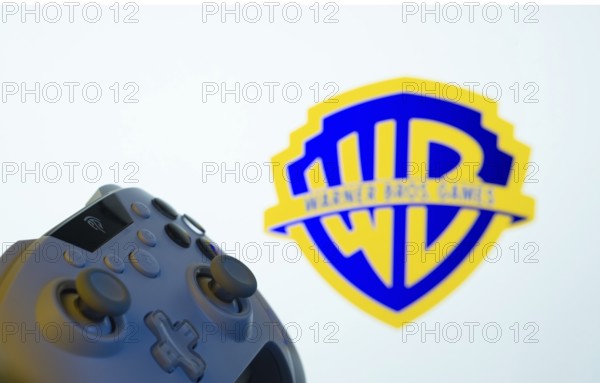 Dhaka, Bangladesh- 14 Nov 2025: A close-up of a gamepad with the Warner Bros. Games seen on screen in the background