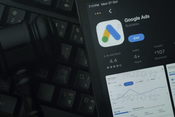 Dhaka, Bangladesh- 28 Oct 2025: An iPad displaying the Google Ads app against a judge's gavel and dark keyboard background