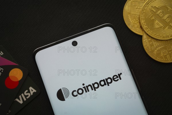 Dhaka, Bangladesh- 03 Sep 2025: Smartphone displaying Coinpaper surrounded by Bitcoin coins and payment cards
