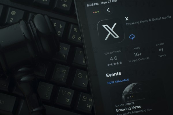 Dhaka, Bangladesh- 28 Oct 2025: An iPad displaying the X app against a judge's gavel and dark keyboard background