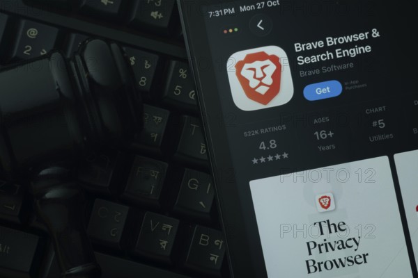 Dhaka, Bangladesh- 28 Oct 2025: An iPad displaying the Brave browser app against a judge's gavel and dark keyboard background