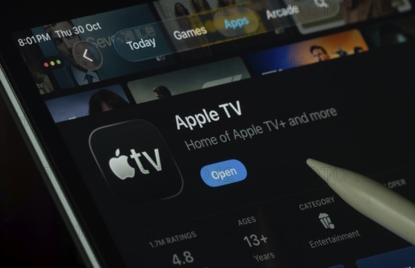 Dhaka, Bangladesh- 30 Oct 2025: Apple TV app displayed on a iPad screen in dark mode with a digital pen pointing at it