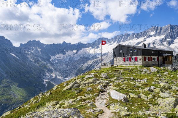Mountain hut Bergseehütte with Swiss flag in picturesque mountain landscape, view of Damma Glacier and Dammastock, Göscheneralp, Canton of Uri, Switzerland
