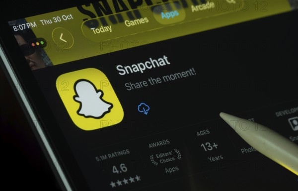 Dhaka, Bangladesh- 30 Oct 2025: Snapchat app displayed on a iPad screen in dark mode with a digital pen pointing at it