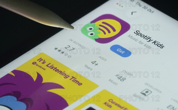 Dhaka, Bangladesh- 30 Oct 2025: Spotify Kids app on a iPad screen with a pen pointing at the install option