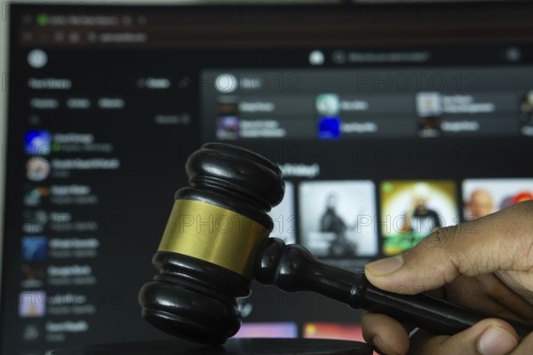 Dhaka, Bangladesh- 20 June 2025: A hand holds a gavel in front of a computer screen displaying Spotify's website