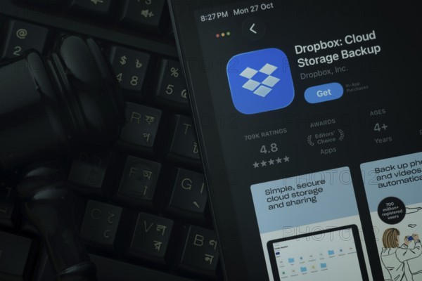 Dhaka, Bangladesh- 28 Oct 2025: An iPad displaying the Dropbox app against a judge's gavel and dark keyboard background
