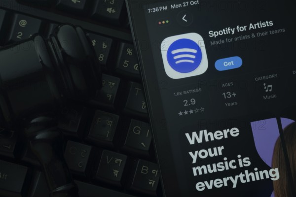 Dhaka, Bangladesh- 28 Oct 2025: An iPad displaying the Spotify for Artist app against a judge's gavel and dark keyboard background