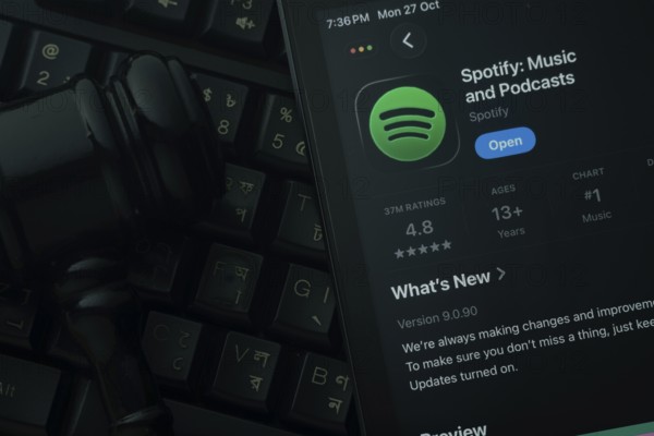 Dhaka, Bangladesh- 28 Oct 2025: An iPad displaying the Spotify app against a judge's gavel and dark keyboard background