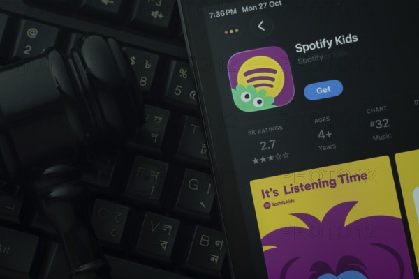 Dhaka, Bangladesh- 28 Oct 2025: An iPad displaying the Spotify Kids app against a judge's gavel and dark keyboard background