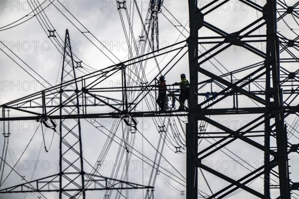 Work on a 380 kV high-voltage overhead line, new construction, along the A57 motorway, near Meerbusch, workers on the boom of the high-voltage pylon, North Rhine-Westphalia, Germany
