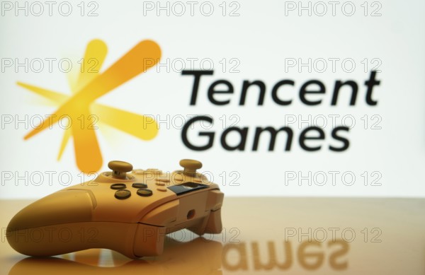 Dhaka, Bangladesh- 14 Nov 2025: A close-up of a white gamepad with the Tencent Games seen on screen in the background
