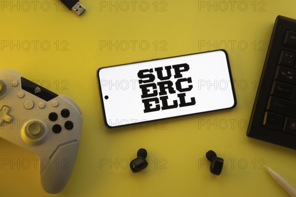 Dhaka, Bangladesh- 23 Mar 2025: Smartphone with Supercell logo, game controller, and earbuds on a yellow background