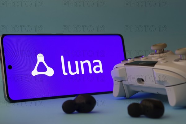 Dhaka, Bangladesh- 23 Mar 2025: A smartphone with a Amazon Luna icon next to a controller and earbuds on a blue surface
