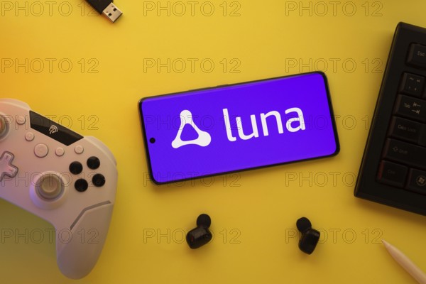 Dhaka, Bangladesh- 23 Mar 2025: Smartphone with Amazon Luna logo, game controller, and earbuds on a yellow background