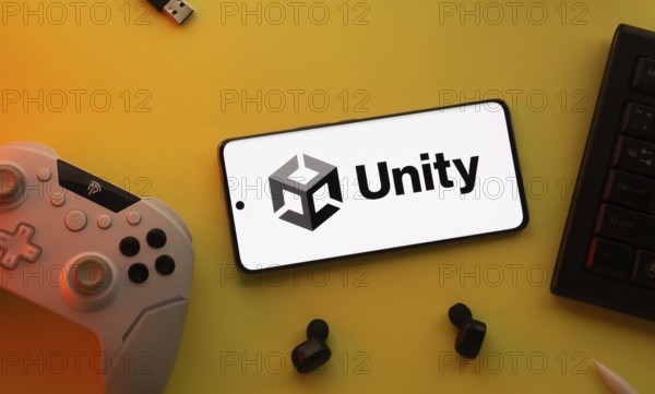 Dhaka, Bangladesh- 23 Mar 2025: Smartphone with Unity logo, game controller, and earbuds on a yellow background