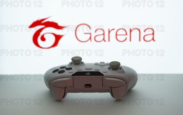 Dhaka, Bangladesh- 19 Sep 2025: A close-up of a white gamepad with the Garena seen on screen in the background