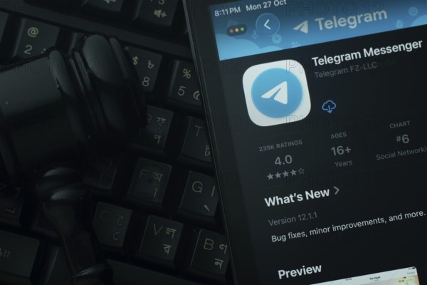 Dhaka, Bangladesh- 28 Oct 2025: An iPad displaying the Telegram app against a judge's gavel and dark keyboard background