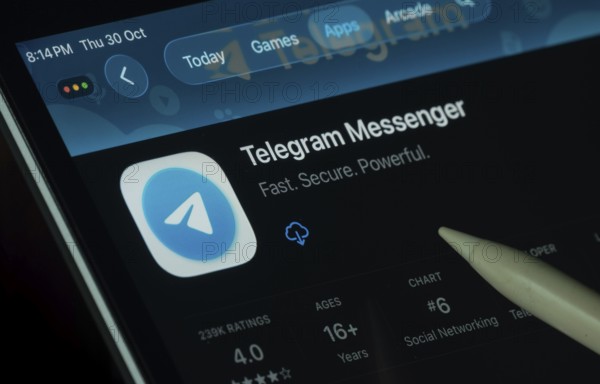 Dhaka, Bangladesh- 30 Oct 2025: Telegram app displayed on a iPad screen in dark mode with a digital pen pointing at it