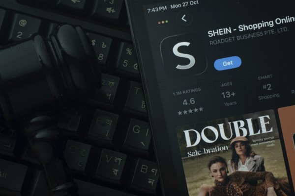 Dhaka, Bangladesh- 28 Oct 2025: An iPad displaying the SHEIN app against a judge's gavel and dark keyboard background