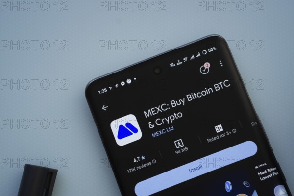Dhaka, Bangladesh- 29 May 2025: On a blue surface, a smartphone displays the MEXC app within the Google Play Store