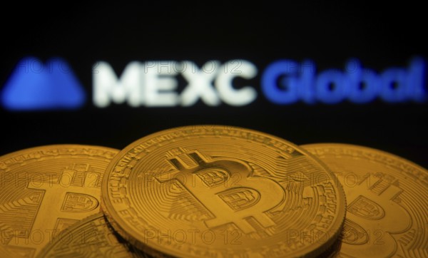 Dhaka, Bangladesh- 03 Sep 2025: Close-up of Bitcoin coins with the MEXC Global logo visible on a screen in the background