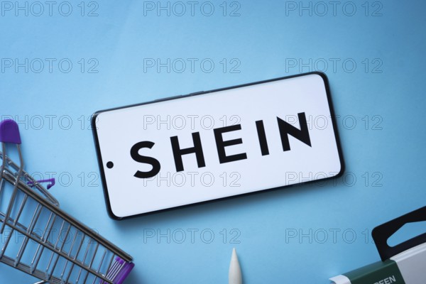 Dhaka, Bangladesh- 03 July 2025: Smartphone displaying SHEIN logo with shopping cart on a blue background