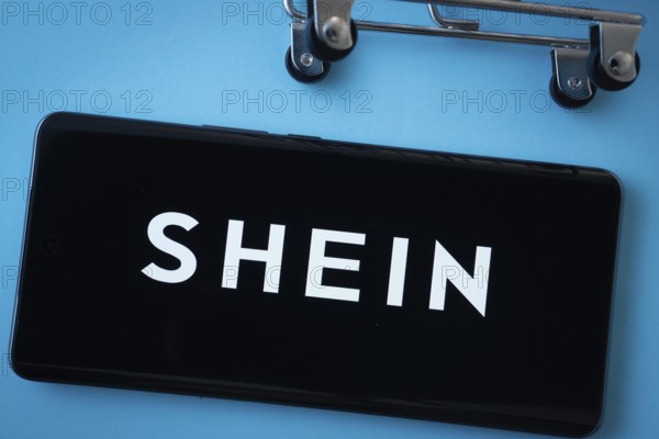 Dhaka, Bangladesh- 03 July 2025: Smartphone screen showing the SHEIN logo with shopping cart wheels on a blue background