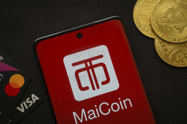 Dhaka, Bangladesh- 06 Sep 2025: Smartphone displaying MaiCoin logo surrounded by Bitcoin coins and payment cards