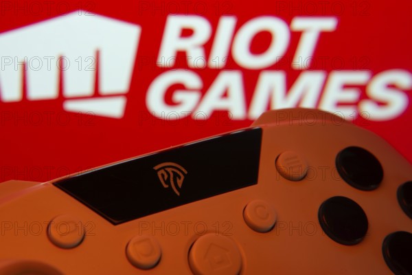 Dhaka, Bangladesh- 14 Nov 2025: A close-up of a gamepad with the Riot Games seen on screen in the background