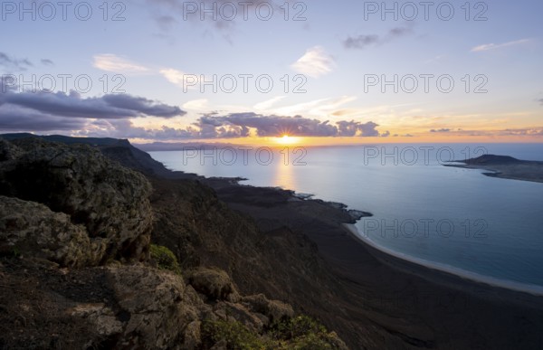 View from steep cliffs to sea and coast with sun stars, Mirador del Porrito viewpoint at sunset, Lanzarote, Canary Islands, Spain