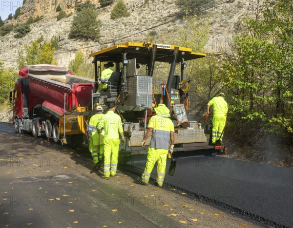 Asphalt road construction team of workers resurfacing tarmac in rural area, near Albarracin, Teruel province, Aragon, Spain