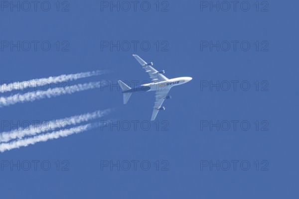 Boeing 747 jumbo jet cargo aircraft of Atlas air airlines flying in a blue sky with contrails or vapour trails behind, England, United Kingdom