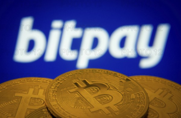 Dhaka, Bangladesh- 26 Aug 2025: Close-up of Bitcoin coins with the bitpay logo visible on a screen in the background