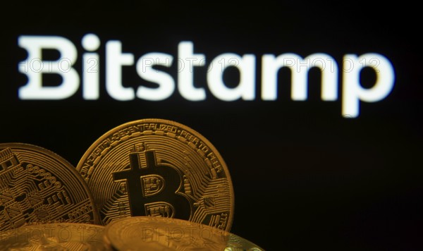 Dhaka, Bangladesh- 03 Sep 2025: Close-up of Bitcoin coins with the Bitstamp logo visible on a screen in the background